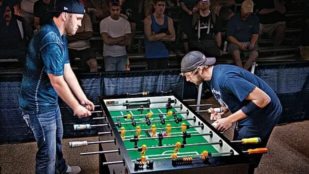 Two guys playing competitive foosball.